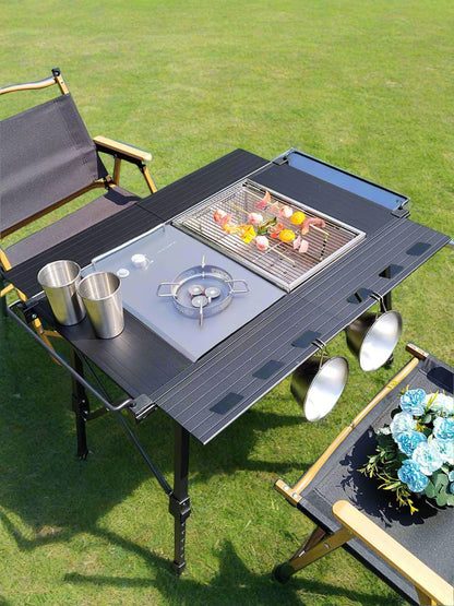 Portable camping grill with cooktop and grilling area on a grassy outdoor setting